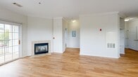 Located at 151 N Main St in Bellingham, Massachusetts, this well-appointed one-bedroom, one-bathroom residence offers a thoughtfully designed single-floor layout. Light hardwood flooring flows throughout the main living areas, complementing the bright, neutral palette that defines the space.

The combined kitchen and living room serves as the heart of the home. The living area features elegant crown molding, a tile-surround gas fireplace, and two large windows that flood the room with natural light and offer pleasant outdoor views. The kitchen is outfitted with crisp white shaker-style cabinetry extending to the ceiling for ample storage, stone countertops, stainless steel appliances including a full-size refrigerator and dishwasher, and a stainless steel sink positioned beneath a window.

The bedroom is carpeted for comfort, features its own window with outdoor views, and provides direct access to both a dedicated closet with hanging space and the full bathroom. The bathroom is finished with clean white tile accented by a classic black tile border, a soaking tub with an overhead shower, and warm wood-look flooring. A hallway connects the living spaces efficiently, completing this functional and modern floor plan.