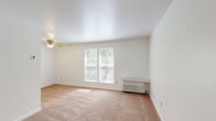 Located at 821-831 Sleepy Hollow Road in Pittsburgh, PA, this one-bedroom, one-bathroom unit offers a practical and comfortable single-floor layout. The combined living and dining area is bright and open, featuring wall-to-wall carpeting, a ceiling fan with light fixture, and a wall-unit HVAC system. Natural light filters in through multiple windows with blinds, offering views of surrounding greenery. The entry door opens directly into this versatile living space, which connects seamlessly to the kitchen. The kitchen is well-equipped with white shaker-style cabinetry, granite-look countertops, a double-basin sink, and white appliances including an electric range and refrigerator, all set over warm hardwood-style flooring. The bedroom is a comfortable, carpeted retreat featuring a large double-door closet, a ceiling fan, and a window that brings in natural light. An additional closet provides extra storage in the unit. The bathroom is clean and functional, featuring a full tub-shower combination with built-in shelving and brushed nickel fixtures, complemented by hardwood-style flooring. A hallway connects the main living areas, completing this efficiently designed and move-in-ready home.