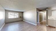 Located at 1869 Coronado Pkwy N in Denver, Colorado, this single-floor, three-bedroom, one-bathroom home offers a practical and well-organized layout. The combined kitchen and living area forms the heart of the home, featuring light wood-look flooring, a textured ceiling, and a wall-mounted A/C unit alongside baseboard heating. Natural light enters through a window with blinds, brightening the open living space, which also includes a ceiling fan. The kitchen is efficiently designed in a galley style, outfitted with white cabinetry, stone-look countertops, a stainless steel sink, and black appliances including a range, dishwasher, refrigerator, and microwave. The three bedrooms offer comfortable accommodations with neutral carpet, textured ceilings, and built-in closets with bifold doors. The primary bedroom provides a generous amount of space. The full bathroom features a clean, tiled tub-shower combination with chrome fixtures and wood-look flooring. Neutral gray tones and white trim are consistent throughout, lending the home a cohesive, move-in-ready aesthetic. A dedicated closet adds additional storage to round out the functional floor plan.