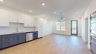 Located in Melbourne, FL, this thoughtfully designed one-bedroom, one-bathroom residence offers a clean, modern aesthetic across a well-appointed single-floor layout. The open-concept living area seamlessly connects the kitchen, dining, and living spaces, all finished with light wood-look flooring and recessed lighting. A ceiling fan and large windows bathe the living room in natural light, with a glass-paned door leading out to a private balcony with outdoor views.

The kitchen is a standout feature, showcasing a stylish two-tone design with crisp white upper cabinetry and slate-blue lower cabinets, complemented by a subway tile backsplash and stainless steel appliances including a refrigerator, range, microwave, and dishwasher.

The carpeted bedroom is a comfortable retreat, featuring dual windows with outdoor views, a ceiling fan, and access to two closets, including a spacious walk-in with wire shelving. The bathroom is elegantly appointed with a dual-sink vanity topped with granite counters, a frameless glass walk-in shower with white tile surround, open shelving, and wood-look flooring. A dedicated laundry area and hallway round out this well-organized and modern home.