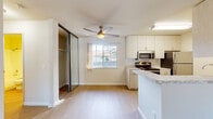 This single-floor California residence offers a clean, functional layout with bright, neutral interiors throughout. The open-concept living and dining area is spacious and inviting, featuring light hardwood-style flooring, a wood-burning fireplace flanked by built-in shelving, and a sliding glass door that leads to an outdoor patio, allowing natural light to fill the room. A ceiling-mounted air conditioning unit ensures year-round comfort.

The kitchen is well-equipped and efficiently designed, featuring stainless steel appliances including an electric range, microwave, refrigerator, and dishwasher. Light wood cabinetry lines both walls of the galley-style layout, complemented by granite-look countertops and a peninsula that opens toward the living area. A ceiling fan with a light fixture and a bright window overlooking the exterior add to the kitchen's airy feel.

The sleeping area includes mirrored sliding closet doors, offering generous storage. The bathroom is clean and functional, with a full tub-shower combination, a granite-topped vanity, and light wood-style flooring. A second bathroom is also present, similarly appointed. Light tones, durable flooring, and a cohesive neutral palette tie the entire space together for a comfortable, move-in-ready living experience.