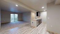 This well-appointed single-floor residence offers a thoughtfully designed open-concept layout that seamlessly connects the living and kitchen areas. The main living space features a combination of light-toned hardwood-style flooring and plush carpeting, with recessed lighting throughout and sliding glass doors that open to a private balcony, allowing natural light to fill the room.

The kitchen is anchored by a peninsula with a built-in sink and stainless steel dishwasher, complemented by sleek dark cabinetry, light countertops, and a full suite of stainless steel appliances including an electric range, over-the-range microwave, and refrigerator — providing a polished, functional cooking space.

The bedrooms are carpeted for comfort, each offering generous proportions and natural light from well-placed windows. Sliding closet doors with built-in shelving and railing systems provide ample storage. Each bedroom also features individual climate control panels for personalized comfort.

The unit includes two bathrooms finished with tile flooring, dark vanity cabinetry, and light countertops. The primary bathroom offers a dual-sink vanity with a wide mirror, while the secondary bathroom features a single-sink configuration — both are clean and efficiently designed. The overall aesthetic is modern and neutral, creating a versatile and inviting living environment.