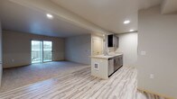This well-appointed single-floor residence offers a thoughtfully designed open-concept layout that seamlessly connects the living and kitchen areas. The main living space features a combination of light-toned hardwood-style flooring and plush carpeting, with recessed lighting throughout and sliding glass doors that open to a private balcony, allowing natural light to fill the room.

The kitchen is anchored by a peninsula with a built-in sink and stainless steel dishwasher, complemented by sleek dark cabinetry, light countertops, and a full suite of stainless steel appliances including an electric range, over-the-range microwave, and refrigerator — providing a polished, functional cooking space.

The bedrooms are carpeted for comfort, each offering generous proportions and natural light from well-placed windows. Sliding closet doors with built-in shelving and railing systems provide ample storage. Each bedroom also features individual climate control panels for personalized comfort.

The unit includes two bathrooms finished with tile flooring, dark vanity cabinetry, and light countertops. The primary bathroom offers a dual-sink vanity with a wide mirror, while the secondary bathroom features a single-sink configuration — both are clean and efficiently designed. The overall aesthetic is modern and neutral, creating a versatile and inviting living environment.