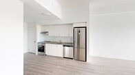 Located at 375 South Street in London, Ontario, this well-appointed 2-bedroom, 1-bathroom unit offers a clean, modern aesthetic throughout its thoughtfully designed single-floor layout. Light-toned hardwood-style flooring runs consistently across the space, complementing the crisp white walls and creating a bright, cohesive atmosphere.

The kitchen is efficiently designed with white flat-front cabinetry extending to the ceiling for maximum storage, a subway tile backsplash, dark countertops, and a full suite of stainless steel appliances including a stove, dishwasher, and tall refrigerator. The open sightlines from the kitchen connect seamlessly to the living area, enhancing the sense of openness.

The primary bedroom is a comfortable retreat featuring a sliding-door closet with built-in hanging storage and neutral white walls. The second bedroom benefits from expansive floor-to-ceiling sliding glass doors with vertical blinds, allowing abundant natural light and offering elevated outdoor views of the surrounding area.

The bathroom is finished with grey tile flooring, a white vanity with a dark countertop, a large mirror, and brushed gold accent hardware, adding a refined touch. The unit's elevated position provides pleasant views visible from both the bedroom and bathroom, enhancing the overall sense of openness and connection to the outdoors.