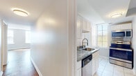 This single-floor residence combines classic design elements with modern updates throughout its thoughtfully laid-out living spaces. Rich parquet hardwood flooring extends across the main living and bedroom areas, adding warmth and timeless character to the interior. Natural light filters generously through multiple gridded windows, brightening each room and offering pleasant outdoor views including glimpses of open water.

The kitchen is well-equipped and contemporary, featuring white shaker-style cabinetry, granite countertops with attractive veining, marble-look porcelain tile flooring, and a full suite of stainless steel appliances including a refrigerator, range, over-the-range microwave, and dishwasher. A modern spring-neck faucet serves the undermount sink, and ample upper and lower cabinet storage provides practical functionality.

The bathroom is finished in a clean, bright aesthetic with large-format marble-look tile on both the floor and shower walls, a floating white vanity, and a window that admits natural light. The living areas are spacious and versatile, with neutral light gray walls, clean white trim, and generous window placement that ensures a bright and airy atmosphere throughout. The overall design presents a cohesive blend of classic architectural details and updated finishes.