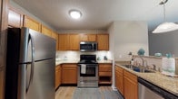 Located at 201 Millstone Rd in Florence, South Carolina, this single-floor unit offers a well-organized layout with functional living spaces throughout. The kitchen is equipped with warm honey-toned wood cabinetry, ample counter space, and white appliances including a refrigerator, electric range, and over-the-range microwave, all set atop hardwood-style flooring that adds a touch of warmth. Adjacent to the kitchen, the living area is generously sized, featuring soft carpeting, neutral walls, and a combination of a wide window and a glass door that bring in natural light and provide outdoor access. The bedrooms are comfortable and well-lit, each featuring ceiling fans with light fixtures, plush carpeting, and windows fitted with blinds for privacy and light control. Two bathrooms serve the unit: one features a white vanity with wood cabinetry, a tub-shower combination, and tile-style flooring, while the second offers a white vanity, toilet, and hardwood-style floors with warm, neutral wall tones. Textured ceilings are consistent throughout, and the overall color palette of soft beiges and whites lends the space a clean, neutral aesthetic well-suited to a variety of décor styles.