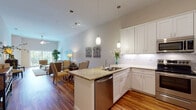Located at 6337 Grand Blvd in New Port Richey, FL, this single-story residence offers a thoughtfully designed open-concept layout that seamlessly connects the kitchen, dining, and living areas. Warm hardwood flooring flows throughout the main living spaces, complementing the bright, neutral color palette that gives the home an airy, welcoming atmosphere.

The kitchen is a standout feature, showcasing white shaker-style cabinetry, granite countertops with a peninsula overhang ideal for casual dining, a stainless steel dishwasher, range, microwave, and refrigerator, along with a classic tile backsplash and elegant pendant lighting. The living room benefits from soaring ceilings and large sliding glass doors that flood the space with natural light and open to a private balcony overlooking lush greenery.

The bedrooms offer plush carpeting and generous windows with outdoor views, creating a calm retreat. A spacious walk-in closet with wire shelving provides ample storage. The bathroom features large-format tile flooring, a tub-shower combination with decorative tile accents, and a white vanity with granite countertops. Throughout, the home maintains a clean, modern aesthetic suited for comfortable Florida living.