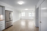 Located at 33 Dunfield in Toronto's Midtown neighbourhood, this two-bedroom, two-bathroom unit offers a thoughtfully designed layout that maximizes its compact footprint. Light-toned hardwood flooring runs throughout, lending warmth and visual continuity across all rooms.

The open-concept kitchen is outfitted with flat-panel white cabinetry extending to the ceiling, a subway tile backsplash, light countertops, and a full suite of stainless steel appliances including a french-door refrigerator, stove, built-in microwave, and dishwasher. The kitchen flows naturally toward the living area, which benefits from dual windows that draw in natural light.

The primary bedroom features a wide window with city views, a mirrored sliding closet, and direct access to a private ensuite bathroom equipped with a glass-enclosed shower stall and white tile surround. The second bedroom is a bright, well-proportioned room with its own window overlooking the cityscape. The second bathroom includes a soaker tub and shower combination with full white tile surround and chrome fixtures.

A hallway connects all rooms efficiently, and the clean, white-toned palette throughout creates a bright, modern ambiance.