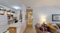 This single-floor residence on Autumn Creek Way in Manchester, Missouri offers a well-organized layout with distinct living spaces connected by a carpeted hallway. The living room is a welcoming area with elevated ceilings, neutral walls, and a large window dressed with sheer curtains that allow generous natural light to filter in, creating a bright and airy atmosphere.

Adjacent to the living room, a dedicated dining area accommodates a round table and seating, providing a defined space for meals. The galley-style kitchen features white cabinetry with warm wood-trimmed accents, ample upper and lower storage, light countertops, and black appliances including a range, dishwasher, and microwave. A breakfast bar connects the kitchen to the main living area.

The bedroom is a comfortable retreat with soft carpet, warm-toned walls, a window overlooking greenery, and a walk-in closet offering generous storage. Two bathrooms serve the residence: one features a vanity with wood-trimmed cabinetry and a walk-in shower with sliding glass doors, while the second includes a vanity, toilet, and tile flooring. Throughout the space, a consistent neutral palette and carpeted floors contribute to a calm, cohesive ambiance.