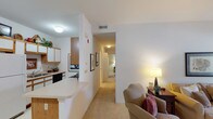 This single-floor residence on Autumn Creek Way in Manchester, Missouri offers a well-organized layout with distinct living spaces connected by a carpeted hallway. The living room is a welcoming area with elevated ceilings, neutral walls, and a large window dressed with sheer curtains that allow generous natural light to filter in, creating a bright and airy atmosphere.

Adjacent to the living room, a dedicated dining area accommodates a round table and seating, providing a defined space for meals. The galley-style kitchen features white cabinetry with warm wood-trimmed accents, ample upper and lower storage, light countertops, and black appliances including a range, dishwasher, and microwave. A breakfast bar connects the kitchen to the main living area.

The bedroom is a comfortable retreat with soft carpet, warm-toned walls, a window overlooking greenery, and a walk-in closet offering generous storage. Two bathrooms serve the residence: one features a vanity with wood-trimmed cabinetry and a walk-in shower with sliding glass doors, while the second includes a vanity, toilet, and tile flooring. Throughout the space, a consistent neutral palette and carpeted floors contribute to a calm, cohesive ambiance.