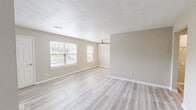 Located in Chesapeake, VA, this 2-bedroom, 2-bathroom home offers a clean, modern aesthetic throughout its single-floor layout. Light-toned luxury vinyl plank flooring runs seamlessly across all living areas, complementing the neutral warm-gray wall palette and crisp white trim. The open combined living and dining area is bright and airy, with multiple windows dressed in white blinds that invite natural light, and a ceiling fan overhead for added comfort. The galley-style kitchen is thoughtfully designed with white shaker cabinetry, granite countertops, a undermount sink with brushed nickel fixtures, and stainless steel appliances. Both bathrooms echo the upscale finishes found in the kitchen, featuring granite-topped vanities with gold-toned hardware and framed mirrors, while one bathroom includes a full tub-shower combo with built-in shelving. The primary bedroom offers a comfortable footprint with access to closets and an en-suite bath, while the second bedroom is equally well-sized with a natural light window. Five closets throughout the home provide generous storage. A dedicated laundry area adds everyday convenience, rounding out this move-in-ready home.