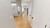 This 420 square foot apartment maximizes space with a thoughtful one-bedroom layout. The open-concept living area combines the kitchen and living room, creating a sense of spaciousness. The kitchen boasts modern white cabinetry, stainless steel appliances, and a subway tile backsplash, offering both style and functionality. The living room features a comfortable sectional sofa, a wall-mounted TV, and a small dining area, all tied together by a vibrant area rug.

The bedroom, while compact at 80 square feet, includes a full-sized bed with a metal frame and is equipped with a wall-mounted air conditioning unit for comfort. The bathroom showcases a clean, white design with a shower/tub combination and built-in shelving for storage.

Throughout the apartment, recessed lighting and light wood flooring contribute to a bright, airy atmosphere. Strategically placed artwork and colorful accents add personality to the neutral color palette. Despite its small footprint, this apartment offers a well-designed living space that balances functionality with modern aesthetics.