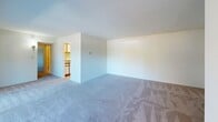Located in the desirable Chevy Chase, MD neighborhood, this single-floor, 2-bedroom, 1-bathroom residence offers a functional and comfortable layout. The living area is open and airy, featuring neutral-toned carpet, clean white walls, and a large sliding glass door that fills the space with natural light and provides views of the surrounding greenery — a notable highlight of the home.

The galley-style kitchen is efficiently designed with ample wood-trimmed cabinetry on both sides, granite-look countertops, light tile flooring, and white appliances including a gas range, refrigerator, and microwave, offering practical storage and cooking space.

The generously sized primary bedroom is a standout feature, offering abundant floor space, plush carpeting, a closet with louvered doors, and a window with views of the outdoors, complemented by a wall sconce for ambient lighting. The secondary bedroom is similarly carpeted and bright, with a closet and neutral finishes throughout.

The bathroom features clean, floor-to-ceiling white tile surrounding a full soaking tub and shower combination, maintaining a crisp and timeless aesthetic. A connecting hallway links the rooms cohesively. Overall, the residence presents a straightforward, well-maintained layout well-suited for comfortable everyday living in a prime Maryland location.
