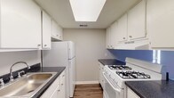 Located at 2400 W Shore Blvd in Columbus, Ohio, this single-floor unit offers a practical and comfortable layout designed for easy living. The spacious living room is highlighted by rich, dark hardwood-style flooring that runs throughout the main areas, large windows that invite abundant natural light, and a sliding glass door with vertical blinds that opens to an outdoor area. A half-wall pass-through seamlessly connects the living space to the kitchen, creating an open, airy feel. The galley-style kitchen is efficiently arranged with white cabinetry offering ample storage on both sides, dark granite-look countertops, a stainless steel sink, a gas range, and a full-size refrigerator. A skylight overhead brightens the kitchen with additional natural light. The bedroom features plush wall-to-wall carpeting and a window with views of the surrounding outdoors, providing a quiet and comfortable retreat. The full bathroom includes a single-sink vanity with a mirrored cabinet, a shower-tub combination, and durable hardwood-style flooring, finished in a clean, neutral palette throughout. This well-maintained unit combines functional design with comfortable living spaces suitable for everyday use.