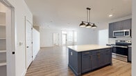 Located in Charlotte's vibrant West End neighborhood, this single-story, 3-bedroom, 2-bathroom home offers a thoughtfully designed open-concept layout. The kitchen is a standout feature, showcasing bold blue-gray shaker cabinets with gold hardware, a white subway tile backsplash, quartz countertops, stainless steel appliances, and a large center island topped with a striking industrial-style pendant light fixture. The kitchen flows seamlessly into the spacious living area, which is finished with light wood-look flooring and recessed lighting throughout. Each bedroom is well-proportioned, featuring ceiling fans, natural light from large windows with blinds, and durable wood-look flooring. The primary bedroom connects to a walk-in closet equipped with wire shelving systems for organized storage. The bathrooms are finished in a clean, modern style with white shaker vanities, quartz countertops, large framed mirrors, and tiled shower surrounds. A dedicated laundry area houses a stacked full-size washer and dryer. Clean white walls, consistent flooring, and ceiling fans throughout the home contribute to a bright, cohesive, and move-in-ready aesthetic ideal for comfortable everyday living.
