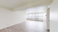 Located at 740 Mississippi River Blvd S in Saint Paul, Minnesota, this single-floor unit offers a clean, light-filled interior with a neutral palette throughout. The main living area is generously proportioned, featuring light wood-tone flooring and a wide bank of floor-to-ceiling windows fitted with vertical blinds. These expansive windows allow abundant natural light to pour in while framing elevated views of the surrounding cityscape, creating an open and airy atmosphere. The layout, visible in the dollhouse view, connects the living space to a dedicated kitchen and a bathroom in a practical, well-organized floor plan. The kitchen is equipped with white cabinetry, granite-style countertops, a mosaic tile backsplash, and white appliances including a refrigerator, electric range, and built-in microwave. Matching the countertops, the bathroom features a granite-topped vanity alongside white square tile walls and flooring. The bathtub and shower combination includes accessibility grab bars and a clean, functional design. Consistent light wood flooring runs throughout the main living spaces, tying the unit together with a cohesive, modern aesthetic. The overall ambiance is bright, minimal, and move-in ready.