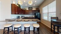 Located at 504 Coventry Lane in Salisbury, Maryland, this single-story community clubhouse offers a thoughtfully designed gathering space for residents. The welcoming entrance foyer features rich hardwood-style flooring, built-in display shelving, and a pendant chandelier, setting an inviting tone throughout the facility.

The main lounge area is bright and airy, with vaulted ceilings, large windows that draw in abundant natural light, and comfortable seating arrangements accented by decorative hexagonal wall shelving. An adjacent dining area includes a round table with seating and direct access to the outdoor patio through full-length glass French doors, offering views of the surrounding community.

The community kitchen is well-equipped with dark wood cabinetry, granite countertops, a peninsula bar with bar stool seating, pendant globe lighting, and full appliances — ideal for social gatherings and events.

The expansive fitness center is divided into distinct zones, with one area housing Matrix strength training equipment, cable machines, and floor mirrors, while a separate cardio room features SportsArt treadmills and elliptical machines, all on durable rubberized flooring with a ceiling fan and wall-mounted television for an enhanced workout experience. Natural light flows through multiple windows throughout the fitness spaces, creating an energizing environment.