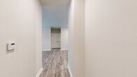 This single-floor unit showcases a cohesive, contemporary design throughout, unified by durable wood-look plank flooring and a neutral color palette of warm whites and soft greiges. The open-concept living and kitchen area provides a generous, connected space anchored by a ceiling fan overhead. The kitchen is well-equipped, featuring crisp white shaker-style cabinetry extending to the upper walls, granite-look countertops, a subway tile backsplash, and a full suite of stainless steel appliances including a range, microwave, dishwasher, and refrigerator. A double-door closet adjacent to the kitchen offers convenient pantry or storage access. The bedrooms are comfortably proportioned, each receiving natural light through blinds-fitted windows and equipped with ceiling fans. A spacious walk-in closet with wire shelving systems provides ample storage. Both bathrooms mirror each other in finish quality, each offering a tub-shower combination with subway tile surround, granite-topped white vanity, and wood-look flooring. Clean white trim and baseboards throughout contribute to the unit's polished, move-in-ready presentation.