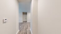 This single-floor unit showcases a cohesive, contemporary design throughout, unified by durable wood-look plank flooring and a neutral color palette of warm whites and soft greiges. The open-concept living and kitchen area provides a generous, connected space anchored by a ceiling fan overhead. The kitchen is well-equipped, featuring crisp white shaker-style cabinetry extending to the upper walls, granite-look countertops, a subway tile backsplash, and a full suite of stainless steel appliances including a range, microwave, dishwasher, and refrigerator. A double-door closet adjacent to the kitchen offers convenient pantry or storage access. The bedrooms are comfortably proportioned, each receiving natural light through blinds-fitted windows and equipped with ceiling fans. A spacious walk-in closet with wire shelving systems provides ample storage. Both bathrooms mirror each other in finish quality, each offering a tub-shower combination with subway tile surround, granite-topped white vanity, and wood-look flooring. Clean white trim and baseboards throughout contribute to the unit's polished, move-in-ready presentation.