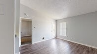 Located at 9101 Avenue Club Drive in Tampa, FL, this one-bedroom, one-bathroom unit offers a practical and efficiently designed single-floor layout. The open-concept living and kitchen area serves as the heart of the space, where wood-look laminate flooring extends throughout, creating a cohesive and easy-to-maintain surface. The kitchen features white cabinetry with brushed nickel hardware, a double-basin stainless steel sink, laminate countertops, and black appliances including a refrigerator and range. A pass-through counter connects the kitchen to the living area, enhancing the sense of openness. The living room receives natural light through a full-length door with sidelight and a window fitted with vertical blinds. A textured popcorn ceiling runs through the main living areas. The bedroom is a well-proportioned room finished with plush carpet, neutral gray walls, and a window with vertical blinds that allows for natural light. The bathroom includes a white vanity with under-sink storage, a granite-style countertop, a well-lit vanity mirror, and carpeted flooring. Overall, the unit presents a clean, neutral palette throughout.
