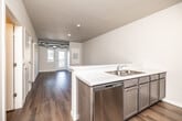 This single-floor residence at 640 Marion Blvd in Marion, Iowa offers a well-designed layout with modern finishes throughout. The open-concept kitchen flows seamlessly into the living area, creating a connected and functional space. The kitchen is equipped with stainless steel appliances—including a refrigerator, range, microwave, and dishwasher—complemented by dark cabinetry, quartz-style countertops, a double-basin sink, and a peninsula that provides additional workspace and a natural division between the kitchen and living area. The living space features durable wood-style flooring and a glass-paneled door that leads to a private balcony, bringing in natural light and outdoor views. Bedrooms are finished with soft carpeting and windows that allow additional natural light. The bathroom includes a single-sink vanity with dark cabinetry, a tub-shower combination, and wood-style flooring. A dedicated laundry area accommodates a full-size washer and dryer. Neutral tones and clean lines are carried throughout the unit, contributing to a cohesive and contemporary aesthetic.