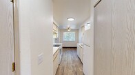 Located at 1915 21st Ave SE in Albany, Oregon, this single-story one-bedroom, one-bathroom unit offers a practical and comfortable layout across a well-utilized floor plan. The galley-style kitchen is efficiently designed with cabinetry lining both sides, white appliances including a range, dishwasher, and refrigerator, a stainless steel sink, and light wood-look flooring that extends into the adjoining living and dining area. The living and dining space benefits from a ceiling fan and a window overlooking outdoor greenery, filling the room with natural light. A second window in the space offers additional views of the surrounding landscape. The spacious bedroom features neutral carpet, a large sliding double-door closet providing ample storage, and a window that brings in natural light. The full bathroom is finished with wood-look flooring, a single vanity with under-sink storage, a toilet, and a full shower-tub combination with a curved rod and grab bar. Throughout the unit, the clean white walls and consistent neutral tones create a cohesive, bright ambiance. The unit also includes access to an outdoor area, visible through windows in both the living space and kitchen.