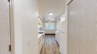 Located at 1915 21st Ave SE in Albany, Oregon, this single-story one-bedroom, one-bathroom unit offers a practical and comfortable layout across a well-utilized floor plan. The galley-style kitchen is efficiently designed with cabinetry lining both sides, white appliances including a range, dishwasher, and refrigerator, a stainless steel sink, and light wood-look flooring that extends into the adjoining living and dining area. The living and dining space benefits from a ceiling fan and a window overlooking outdoor greenery, filling the room with natural light. A second window in the space offers additional views of the surrounding landscape. The spacious bedroom features neutral carpet, a large sliding double-door closet providing ample storage, and a window that brings in natural light. The full bathroom is finished with wood-look flooring, a single vanity with under-sink storage, a toilet, and a full shower-tub combination with a curved rod and grab bar. Throughout the unit, the clean white walls and consistent neutral tones create a cohesive, bright ambiance. The unit also includes access to an outdoor area, visible through windows in both the living space and kitchen.