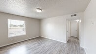 Located at 633 W Vandament Ave in Yukon, Oklahoma, this single-floor, one-bedroom, one-bathroom unit delivers a functional and efficiently designed living space. The open living area greets residents upon entry, featuring durable wood-look vinyl plank flooring, neutral warm-gray walls, and a textured ceiling with flush-mount lighting. A ceiling fan extends into the adjoining space, promoting comfortable airflow. A front-facing window with blinds fills the living area with natural light and outdoor views.

The kitchen is thoughtfully appointed with white upper cabinetry, gray lower cabinets, a subway tile backsplash, stone-look countertops, and black appliances including a range and a full-size refrigerator. An open shelf above the sink adds both storage and visual interest.

The bedroom offers plush wall-to-wall carpeting, a ceiling fan with light fixture, a window overlooking the outdoors, and a dedicated closet, creating a comfortable and private retreat.

The bathroom features wood-look flooring, a vanity with stone-look countertop, gray cabinetry, and a full tub-shower combination. A hallway connects all spaces seamlessly, completing this well-organized and move-in-ready unit.