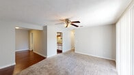 This single-story, 2-bedroom, 2-bathroom residence in Hattiesburg, Mississippi offers a well-organized floor plan designed for comfortable everyday living. The spacious living area features neutral-toned carpet, a ceiling fan with light fixture, and a textured ceiling, creating a bright and airy atmosphere. The open sightline from the living room directly into the kitchen enhances the sense of connectivity throughout the main living space. The kitchen is equipped with white cabinetry accented by wood trim, granite-style laminate countertops, a double-basin sink, a dishwasher, a refrigerator, and an electric range. Rich hardwood-style flooring in the kitchen adds a warm contrast to the lighter tones found throughout the rest of the home. A dedicated hallway leads to both bedrooms, each featuring plush carpet, ceiling fans, and windows that allow natural light to filter in. One bedroom includes a window with a view of surrounding greenery. The bathrooms feature hardwood-style flooring, a tub-shower combination, a single vanity with granite-style countertops, and clean, simple finishes. Additional storage is accessible via a pantry or closet space off the kitchen area. The neutral color palette and consistent finishes throughout give the home a cohesive and move-in-ready appeal.