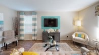 This single-story residence is thoughtfully designed with a cohesive teal, gray, and neutral color scheme that carries through each room. The living area serves as the central gathering space, featuring wood-look hard flooring, a textured ceiling, and a bold teal accent wall that frames the mounted flat-screen television. Natural light filters in through horizontal blinds and striped drapery panels, creating a bright and welcoming atmosphere. A front entry door opens directly into this space, adding convenience.

The kitchen is efficiently laid out with dark gray cabinetry, granite-style countertops, a stainless steel double sink, and black appliances including an electric range and over-the-range microwave. Wood-look flooring continues here, maintaining visual consistency.

The bedroom is carpeted for comfort and features a sliding glass door that opens to an outdoor balcony, offering exterior views and added natural light. Vertical blinds and layered curtain panels provide privacy and light control.

The bathroom includes a vanity with navy cabinetry, granite countertops, a large mirror with overhead lighting, and a separate water closet. A secondary mirror with a chrome frame is visible in the hallway adjacent to the vanity area, adding functionality to the space.