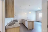Located at 185 Pearl St in downtown Burlington, Vermont, this one-bedroom, one-bathroom unit offers a thoughtfully designed layout across a single floor. A defining architectural feature throughout the space is the white-painted exposed brick, lending an urban, loft-inspired character to every room.

The kitchen is efficiently arranged with light wood cabinetry, a full suite of white appliances including a range and refrigerator, and a concrete-topped island with bar seating that doubles as a dining area. Globe pendant lights hang above the island, adding a warm, modern touch. The white brick backsplash carries the industrial aesthetic seamlessly into the cooking space.

The combined living and dining room benefits from large windows that invite natural light and provide views of the surrounding Burlington streetscape. The bedroom is a cozy, well-defined space featuring the same white brick accent wall, two closets for ample storage, and windows that frame outdoor views.

The bathroom is clean and modern, featuring a light wood vanity, round mirror, and neutral flooring, maintaining the consistent contemporary aesthetic found throughout the unit. Two closets provide practical storage solutions. This unit offers a distinctive urban feel rooted in Burlington's vibrant Pearl Street corridor.