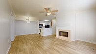 This single-story, one-bedroom, one-bathroom residence offers a thoughtfully designed layout that maximizes its generous footprint. The open-concept living and dining area serves as the heart of the home, featuring light wood-look flooring, a ceiling fan with integrated lighting, and a tile-surround fireplace with a classic white mantel that adds a focal point to the space. Pendant lighting delineates the dining zone, while an adjoining room with additional ceiling fan and access to the outdoors via a windowed door provides flexible living space filled with natural light.

The galley-style kitchen is equipped with black appliances, including a refrigerator, microwave, and electric range, complemented by white cabinetry with wood accents and a pass-through that connects to the main living area. A washer and dryer hookup area is conveniently accessible from the kitchen.

The bedroom is carpeted and generously sized, featuring a walk-in closet with wire shelving and a textured ceiling. The full bathroom includes a tub-shower combination, a vanity with a white countertop and wood-trimmed cabinetry, and wood-look tile flooring throughout. The overall palette of neutral tones creates a clean, move-in-ready ambiance.