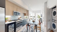 This thoughtfully designed 2-bedroom, 1-bathroom residence maximizes every square foot with a smart open-plan layout and high-end contemporary finishes throughout. The kitchen is a standout feature, equipped with full stainless steel appliances including a gas range, built-in microwave, French door refrigerator, dishwasher, and a wine cooler. Light wood upper cabinetry is paired with dark lower cabinets and a neutral tile backsplash, creating a striking two-tone aesthetic over light hardwood flooring. The kitchen flows seamlessly into the dining area and living room, making the space ideal for both daily living and entertaining. The living room is bathed in natural light from large floor-to-ceiling windows that offer open city views, with soaring ceilings that enhance the airy feel of the space. Both bedrooms are comfortably proportioned, featuring large windows, clean white walls, and light hardwood floors. The primary bedroom benefits from its own window with views. The bathroom is finished with a warm wood vanity, white quartz countertop, an illuminated LED mirror, and a glass-enclosed shower, delivering a clean, spa-like atmosphere. Throughout the residence, a cohesive palette of whites, natural woods, and soft neutrals creates a bright and welcoming environment.