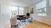 Located at 120 Park St in Bristol, Connecticut, this well-appointed single-floor residence offers a thoughtfully designed layout that balances comfort and functionality throughout. The spacious living room immediately captures attention with its striking ornate coffered ceiling, warm hardwood flooring, and an array of large windows that flood the space with natural light while offering views of the surrounding greenery. The room comfortably accommodates a seating arrangement centered around a colorful area rug, creating an inviting atmosphere for relaxation or entertaining.

The kitchen is a standout feature, equipped with stainless steel appliances, including a refrigerator, range, microwave, and dishwasher. Soft grey cabinetry pairs elegantly with granite countertops, and a peninsula provides additional prep space and casual dining. Large windows in the kitchen maintain the bright, airy feel found throughout the home.

The bedrooms are serene and well-proportioned, each featuring the same rich hardwood floors and generous closet space. Natural light enters through sizable windows, contributing to a calm and restful environment.

The bathroom is clean and functional, featuring tile flooring, a vanity with under-cabinet storage, and a mirrored medicine cabinet. Consistent finishes and warm neutral tones throughout the home create a cohesive and welcoming aesthetic.