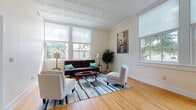 Located at 120 Park St in Bristol, Connecticut, this well-appointed single-floor residence offers a thoughtfully designed layout that balances comfort and functionality throughout. The spacious living room immediately captures attention with its striking ornate coffered ceiling, warm hardwood flooring, and an array of large windows that flood the space with natural light while offering views of the surrounding greenery. The room comfortably accommodates a seating arrangement centered around a colorful area rug, creating an inviting atmosphere for relaxation or entertaining.

The kitchen is a standout feature, equipped with stainless steel appliances, including a refrigerator, range, microwave, and dishwasher. Soft grey cabinetry pairs elegantly with granite countertops, and a peninsula provides additional prep space and casual dining. Large windows in the kitchen maintain the bright, airy feel found throughout the home.

The bedrooms are serene and well-proportioned, each featuring the same rich hardwood floors and generous closet space. Natural light enters through sizable windows, contributing to a calm and restful environment.

The bathroom is clean and functional, featuring tile flooring, a vanity with under-cabinet storage, and a mirrored medicine cabinet. Consistent finishes and warm neutral tones throughout the home create a cohesive and welcoming aesthetic.