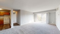 This single-floor unit offers a well-organized layout designed for comfortable everyday living. The living area is generously sized, finished with neutral-toned carpet and light gray walls that create a bright, clean atmosphere. A sliding glass door leads to a private balcony, allowing natural light to fill the space while providing views of surrounding greenery. An HVAC vent is integrated into the ceiling, ensuring year-round climate control.

Adjacent to the living area, the kitchen features warm-toned oak cabinetry extending to the upper walls for ample storage, complemented by light granite-style countertops, a double sink, and wood-look vinyl flooring. White appliances, including a gas range and refrigerator, are included.

The bedrooms are carpeted and finished with the same neutral palette, each offering generous proportions. One bedroom includes a walk-in closet with built-in shelving, providing substantial storage. A window in one bedroom frames views of mature trees, enhancing the connection to the outdoors.

The bathroom includes a full tub-shower combination with white tile surround, a wood-toned vanity with a white countertop, and wood-look flooring, completing the unit's functional and cohesive design.