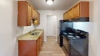 Located at 35 Old Carriage Rd in West Warwick, Rhode Island, this one-bedroom, one-bathroom residence offers a practical and well-organized single-floor layout. The galley-style kitchen is a standout feature, equipped with warm wood cabinetry, granite countertops, a stainless steel sink, and black appliances including an electric range and refrigerator. Light hardwood-style flooring runs through the kitchen, hallway, and living areas, lending a clean, cohesive look throughout. The living room is bright and open, featuring a ceiling fan with integrated lighting and a pass-through architectural detail that adds visual interest. A separate dining area completes the main living space. The bedroom offers cozy carpeting, neutral taupe walls, and access to multiple closets — five in total throughout the unit, providing exceptional storage for a residence of this size. The bathroom is neatly appointed with a full tub and shower combination, pedestal sink, toilet, and hardwood-style flooring. Crisp white trim, panel-style doors, and neutral wall tones throughout create a clean, move-in-ready aesthetic. The hallway connects all areas efficiently, making the floor plan feel intuitive and functional.