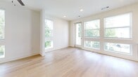 Located at 1200 Foster St NW in Atlanta's vibrant West Midtown neighborhood, this studio unit offers a well-designed, single-floor layout that efficiently combines living and kitchen spaces. Light hardwood flooring runs throughout, complementing the crisp white walls and recessed lighting to create a bright, clean aesthetic. The open living area is bathed in natural light, courtesy of multiple large windows and a glass-panel door that frames lush outdoor greenery and provides direct access to the outdoors. The kitchen is a standout feature, outfitted with bold dark cabinetry, stainless steel appliances including a refrigerator, electric range, over-the-range microwave, and dishwasher, as well as open metal floating shelves and a white countertop with an undermount sink. A classic white subway tile backsplash adds a modern touch. The bathroom continues the contemporary design language with dark vanity cabinetry, matte black hardware accents, a white countertop, and wood-look flooring. A dedicated closet provides practical storage. The overall ambiance of the unit is modern, minimalist, and airy, making efficient use of its compact footprint.