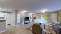 This well-appointed single-floor residence offers four bedrooms and four bathrooms, thoughtfully designed to maximize functionality and comfort. The open living room serves as the heart of the home, featuring light wood-style flooring, a ceiling fan, and ample space for seating and entertainment. Large windows invite natural light, creating a bright and welcoming atmosphere throughout.

The kitchen is outfitted with white cabinetry, generous countertop space, and a full suite of appliances including an electric range, dishwasher, and over-the-range microwave — well-suited for everyday cooking and shared living.

Each of the four bedrooms is a private suite with its own bathroom, offering independence and convenience. The bedrooms feature plush carpeting and individual in-room amenities, including a dedicated workspace area, mini-refrigerator, and microwave in select rooms — ideal for student or professional living. Closets with built-in shelving provide practical storage solutions.

Three hallways connect the layout efficiently, ensuring smooth flow between spaces. The bathrooms are clean and functional, each featuring a tub-shower combination. Throughout the residence, a neutral color palette of soft grays and whites creates a calm, cohesive aesthetic that is both modern and livable.