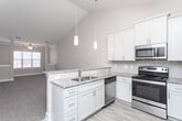 Located at 5301 Williamsburg Station Ln in Greensboro, NC, this single-floor residence offers a thoughtfully designed layout with a blend of modern finishes and functional spaces throughout.

The kitchen serves as a central highlight, featuring white shaker-style cabinetry extending to the ceiling, granite countertops, a classic subway tile backsplash, and a full suite of stainless steel appliances including a refrigerator, range, microwave, and dishwasher. Light hardwood-style flooring adds warmth to the space. A peninsula with a granite overhang and pendant lighting above connects the kitchen to the adjacent living area, which transitions to plush carpeting.

The bedrooms are carpeted and benefit from vaulted ceilings that lend a generous sense of height and openness. Ceiling fans with integrated lighting provide comfort and airflow, while windows allow natural light to filter in. One bedroom includes access to a spacious walk-in closet outfitted with multi-level wire shelving systems, offering substantial storage capacity.

The bathroom features tile flooring, a vanity with granite countertops, dark cabinetry, and classic panel doors. Neutral tones and clean white trim carry throughout the home, creating a cohesive and move-in-ready aesthetic.