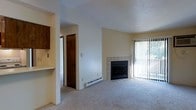 Located at 238 52nd Street in West Des Moines, Iowa, this single-floor residence offers a comfortable and functional layout designed for everyday living. The living area serves as the heart of the space, anchored by a tile-surround fireplace that adds warmth and a focal point to the room. Soft carpeting underfoot enhances the inviting atmosphere, while a full-height sliding glass door with vertical blinds allows for natural light and provides access to the outdoors. The textured ceiling and neutral wall tones throughout give the space a clean, understated aesthetic. Adjacent to the living area, the kitchen is partially visible and features dark wood cabinetry, offering ample storage. A pass-through or built-in shelf detail connects the kitchen zone to the living space, adding a practical architectural element. A hallway leads to additional rooms, with dark wood doors providing clear separation between living and private spaces. Baseboard heating is present along the walls, ensuring efficient climate control throughout the unit. Overall, the space presents a straightforward and well-organized floor plan suited for comfortable residential living.