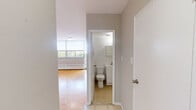 Located on the 9th floor at 120 Shelborne Avenue in Toronto's vibrant midtown neighbourhood, this one-bedroom, one-bathroom unit offers an efficiently designed layout across a single floor. The spacious primary bedroom is the heart of the unit, featuring warm parquet hardwood flooring laid in a classic basket-weave pattern, neutral grey walls, and clean white baseboards that give the room a bright, airy feel. The open sightlines and generous proportions make the bedroom a comfortable and versatile living space. The kitchen is thoughtfully appointed with white cabinetry extending to the ceiling for maximum storage, a marble-look countertop, a stainless steel refrigerator, and a stainless steel range. Light ceramic tile flooring completes the kitchen's clean, practical aesthetic. The bathroom is finished with white square wall tiles surrounding a full soaking tub with an overhead shower, a wall-mounted mirror cabinet, and a white vanity, creating a bright and functional space. The unit's neutral palette and classic finishes provide a clean canvas well-suited for a variety of living arrangements. Its location at Shelborne Avenue places residents close to parks, transit, and the amenities of the Lawrence and Bathurst area of Toronto.