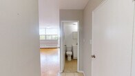 Located on the 9th floor at 120 Shelborne Avenue in Toronto's vibrant midtown neighbourhood, this one-bedroom, one-bathroom unit offers an efficiently designed layout across a single floor. The spacious primary bedroom is the heart of the unit, featuring warm parquet hardwood flooring laid in a classic basket-weave pattern, neutral grey walls, and clean white baseboards that give the room a bright, airy feel. The open sightlines and generous proportions make the bedroom a comfortable and versatile living space. The kitchen is thoughtfully appointed with white cabinetry extending to the ceiling for maximum storage, a marble-look countertop, a stainless steel refrigerator, and a stainless steel range. Light ceramic tile flooring completes the kitchen's clean, practical aesthetic. The bathroom is finished with white square wall tiles surrounding a full soaking tub with an overhead shower, a wall-mounted mirror cabinet, and a white vanity, creating a bright and functional space. The unit's neutral palette and classic finishes provide a clean canvas well-suited for a variety of living arrangements. Its location at Shelborne Avenue places residents close to parks, transit, and the amenities of the Lawrence and Bathurst area of Toronto.