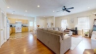 This two-story apartment at Savannah Square in Auburn, Alabama offers a well-organized layout across two levels. The main level features an open-concept design where the living, dining, and kitchen areas flow seamlessly together. The living room is generously sized, showcasing warm hardwood flooring, recessed lighting, a ceiling fan, and multiple windows that allow ample natural light. A built-in shelving and desk area along one wall provides a convenient workspace.

The dining area sits adjacent to the living room, featuring a distinctive checkered tile floor that extends into the kitchen. The kitchen is equipped with light wood cabinetry, dark countertops, white appliances including a dishwasher and range, and a window above the sink for added brightness.

Both bedrooms are comfortably sized and carpeted, each featuring ceiling fans. The primary bedroom includes access to a private bathroom with a white vanity, large mirror, and stylish light fixture. The second full bathroom, also featuring a white vanity and shower/tub combination, continues the clean, neutral aesthetic found throughout the unit. A staircase connects the two floors, completing this practical and inviting layout.