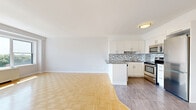 Located on the fourth floor at 1745 Avenue Cedar in Montréal, this well-appointed one-bedroom, one-bathroom unit offers a comfortable and functional layout across a single floor. The open-concept living and kitchen area serves as the heart of the unit, filled with abundant natural light streaming through a large floor-to-ceiling window wall that frames views of the surrounding Montréal cityscape and provides direct access to a private balcony. Classic parquet flooring runs throughout the living spaces, adding warmth and character to the bright, neutral-toned interiors. The kitchen is thoughtfully designed with crisp white cabinetry, a mosaic tile backsplash, stone-look countertops, a peninsula breakfast bar, and a full suite of stainless steel appliances, including a refrigerator, stove, and built-in microwave. The bedroom is a well-proportioned, quiet retreat featuring the same parquet flooring, neutral walls, and a window with outdoor views. The bathroom is finished with large-format floor tiles, full tub and shower surround in neutral stone-toned tile, and clean white fixtures. A hallway connects the rooms, completing this efficiently organized and move-in-ready urban residence.