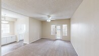 Located in Chandler, Arizona, this single-story 2-bedroom, 1-bathroom residence offers a practical and comfortable layout. The living area is bright and open, featuring plush carpeting, a ceiling fan with light fixture, and a glass-paneled door flanked by windows that allow natural light to fill the space and provide outdoor views. The kitchen is thoughtfully designed in a galley style with crisp white cabinetry, light countertops, wood-look flooring, and white appliances including a coil-top range, built-in microwave, and refrigerator. A window at the end of the kitchen brings in additional natural light, and the layout opens conveniently into a dedicated dining area. The primary bedroom offers a comfortable footprint, carpet flooring, a ceiling fan, and a large window with outdoor views. A standout feature is the walk-in closet, which includes dual hanging rods and a central built-in shelving unit for ample organized storage. The second bedroom is similarly appointed with carpet and a ceiling fan. The bathroom features wood-look flooring, a white vanity with a large mirror, and a separate tub/shower combination. Textured ceilings are present throughout the living spaces, adding a classic residential character to the home.