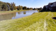 Located at 7457 N Kensington Way in McCordsville, Indiana, this single-story property offers a peaceful setting complemented by impressive outdoor surroundings. The exterior landscape is one of the home's most notable features, with a generously sized, well-maintained lawn that slopes gently toward a picturesque pond. The water feature adds a tranquil, reflective quality to the property, with calm waters mirroring the open sky and surrounding greenery. Mature trees of varying species frame the perimeter, providing both natural beauty and a sense of established landscaping. The grounds are thoughtfully maintained, with lush, evenly cut grass that enhances the overall curb appeal. The setting offers an open, airy feel, benefiting from abundant natural light and unobstructed views across the water. The combination of the pond, verdant lawn, and tree-lined backdrop creates a serene outdoor environment ideal for quiet enjoyment. Situated in the McCordsville community of Hancock County, the property enjoys a suburban setting with a distinctly natural ambiance, making it a standout location for those who appreciate scenic, tranquil surroundings.