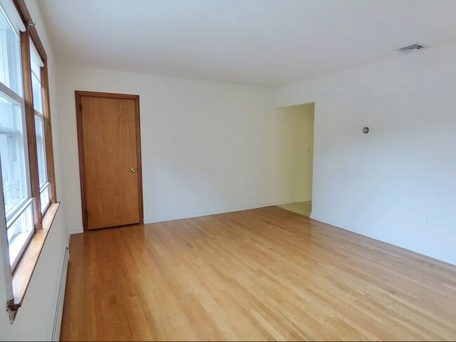 Sunny living room with hardwood floors and coat closet. - 3 Grange St