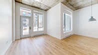 This contemporary condo in Montreal offers a harmonious blend of modern design and practical living. Spanning 93 square meters across two floors, the space includes three bedrooms, two bathrooms, and an open-concept kitchen and living area. The primary bedroom, measuring 11 square meters, provides a spacious retreat.

The interior is characterized by its sleek, minimalist aesthetic. Light wood flooring runs throughout, complementing the crisp white walls and creating a bright, airy atmosphere. Large windows in the living areas and bedrooms flood the space with natural light and offer views of the surrounding urban landscape.

The kitchen boasts a modern design with gray cabinetry, stainless steel appliances, and a central island with a white countertop, perfect for casual dining or food preparation. The bathrooms feature contemporary fixtures, including a combination of white and gray tiling.

A unique architectural element is the exposed concrete ceiling in some areas, adding an industrial-chic touch to the otherwise polished interior. The condo also includes in-unit laundry facilities, enhancing convenience for residents.

Located at 2350 Rue Saint-Patrick in Montreal, this property combines style and functionality in a desirable urban setting.