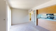 Located at 2299 N Silverbell Rd in Tucson, Arizona, this one-bedroom, one-bathroom unit offers a practical and efficient single-floor layout. The carpeted living room provides a comfortable gathering space and connects seamlessly to a pass-through kitchen, which features warm wood cabinetry, light countertops, stainless steel appliances including an electric range, over-the-range microwave, dishwasher, and a sink — all set over durable hardwood-style flooring. A built-in pantry with open shelving adds valuable storage to the kitchen area. The bedroom is a well-proportioned, carpeted retreat with a large window fitted with vertical blinds, allowing natural light to brighten the space. A closet in the bedroom houses a stacked in-unit washer and dryer, a convenient and practical feature. The bathroom is neatly appointed with a tiled tub-shower combination, a wood-vanity with sink, and hardwood-style flooring. Neutral tones and textured ceilings are consistent throughout, giving the unit a clean, cohesive aesthetic. A hallway connects the main living areas, contributing to the space's organized flow. This unit is well-suited for those seeking a streamlined, low-maintenance living space in Tucson.
